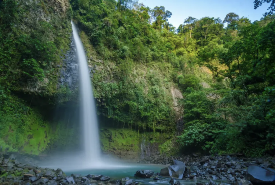 A waterfall cascades over a lush, green rock wall in Costa Rica.